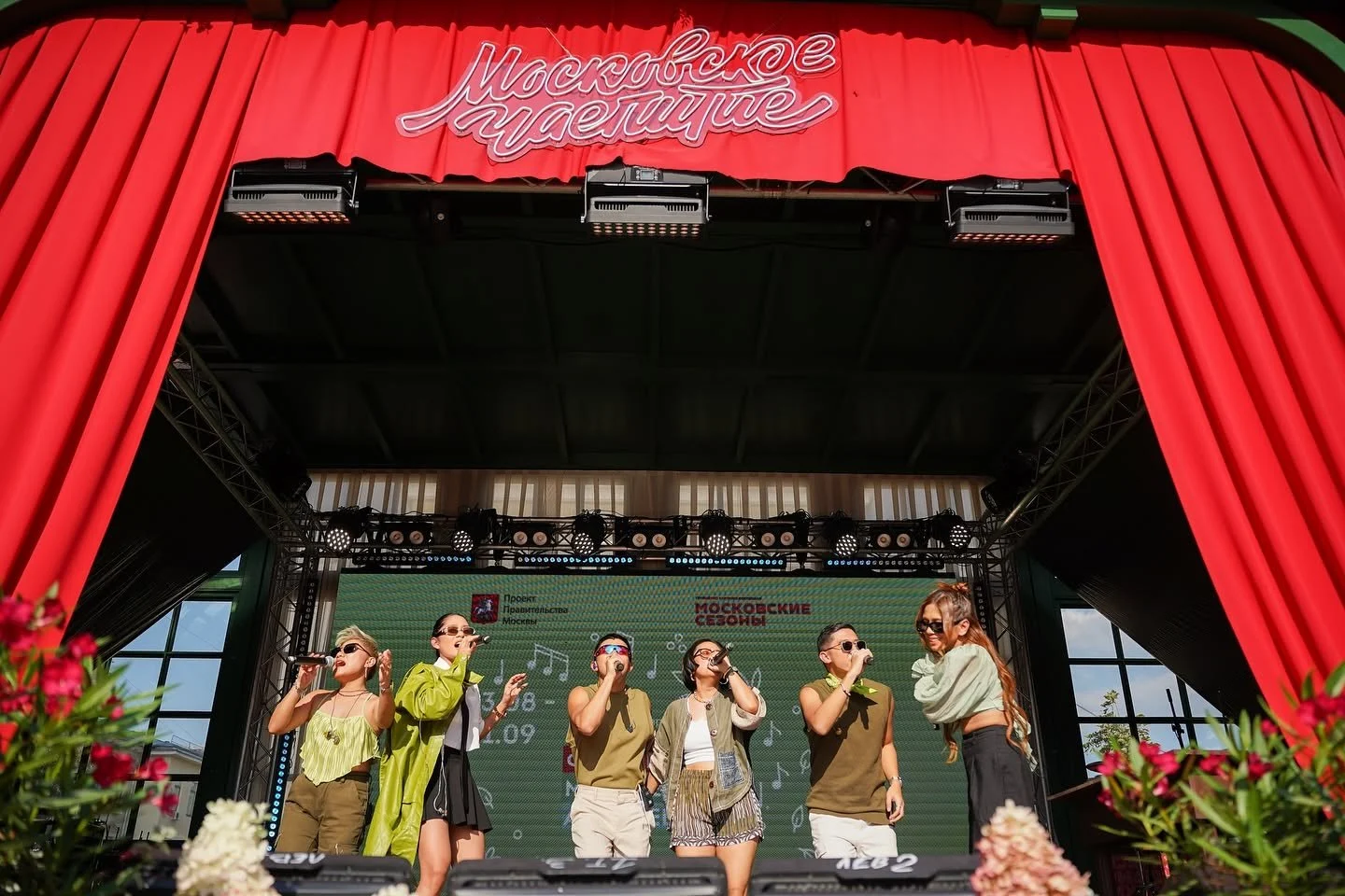 Pinopela performing on an open-air festival stage with red curtains in Moscow